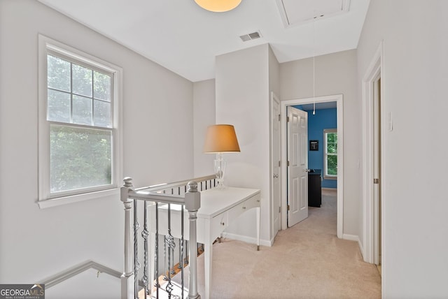 hall with light colored carpet, attic access, visible vents, and baseboards