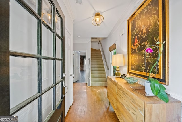 foyer with stairway, ornamental molding, light wood-style flooring, and visible vents