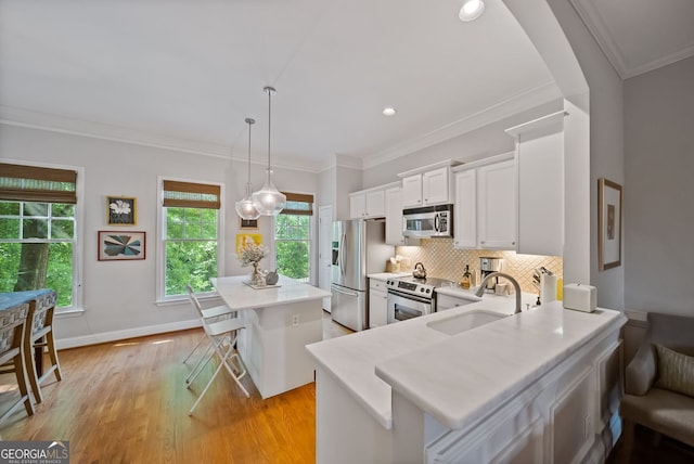 kitchen with stainless steel appliances, a center island, a sink, white cabinetry, and light countertops