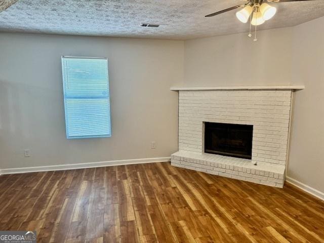 3988 Chimney Ridge Dr, Ellenwood, GA 30294 - unfurnished living room with wood finished floors, a ceiling fan, a brick fireplace, a textured ceiling, and baseboards