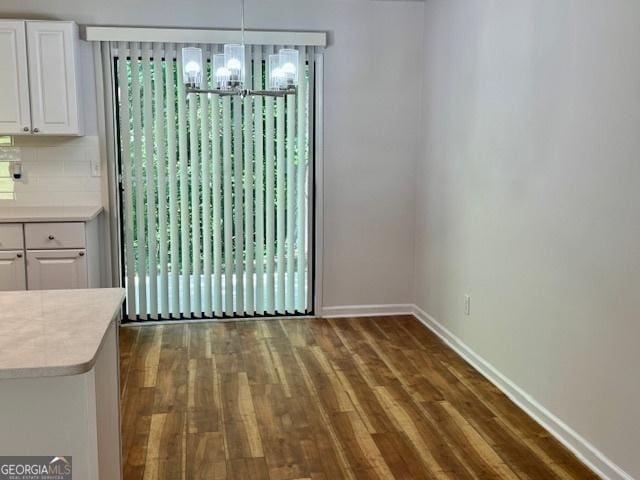 3988 Chimney Ridge Dr, Ellenwood, GA 30294 - unfurnished dining area with dark wood finished floors, a chandelier, and baseboards