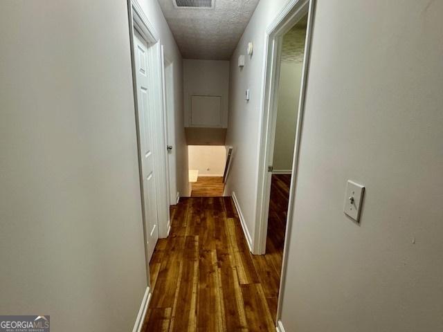 3988 Chimney Ridge Dr, Ellenwood, GA 30294 - corridor with dark wood finished floors, visible vents, baseboards, and a textured ceiling