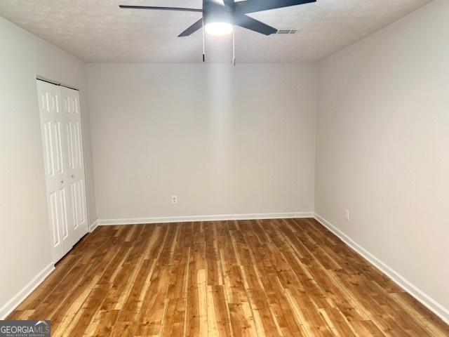 3988 Chimney Ridge Dr, Ellenwood, GA 30294 - empty room with baseboards, wood finished floors, a ceiling fan, and visible vents