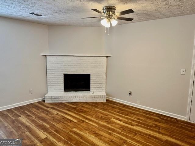 3988 Chimney Ridge Dr, Ellenwood, GA 30294 - unfurnished living room featuring wood finished floors, a textured ceiling, ceiling fan, a brick fireplace, and baseboards