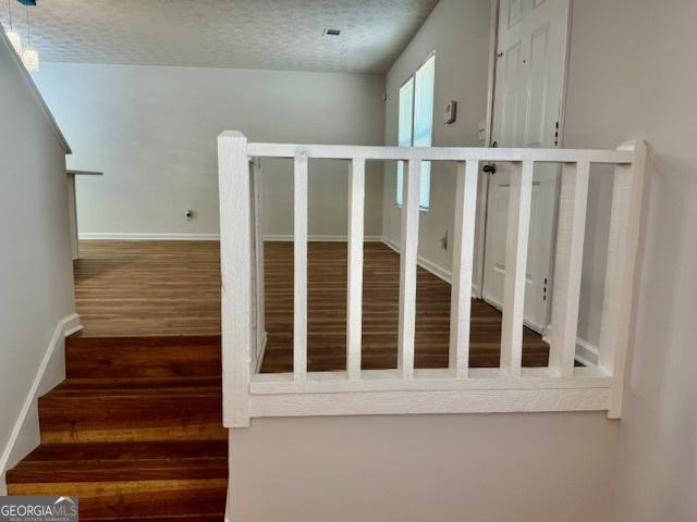 3988 Chimney Ridge Dr, Ellenwood, GA 30294 - staircase with a textured ceiling, wood finished floors, and baseboards
