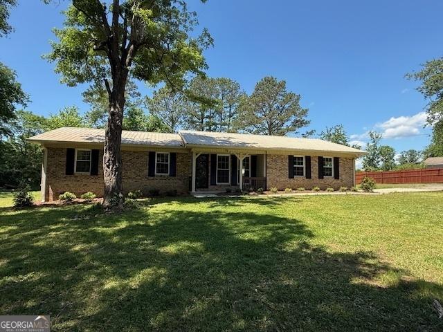 single story home featuring fence, a front lawn, and brick siding