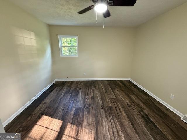 unfurnished room with baseboards, a ceiling fan, and dark wood-style floors
