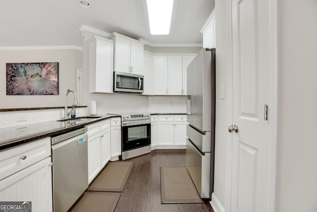 kitchen featuring a sink, crown molding, backsplash, stainless steel appliances, and white cabinets