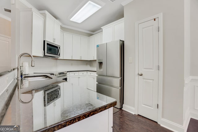 kitchen featuring a sink, stainless steel appliances, white cabinets, dark wood finished floors, and decorative backsplash