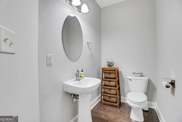 half bathroom with toilet, baseboards, and wood finished floors