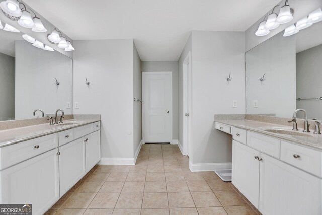full bath featuring tile patterned flooring, baseboards, two vanities, and a sink