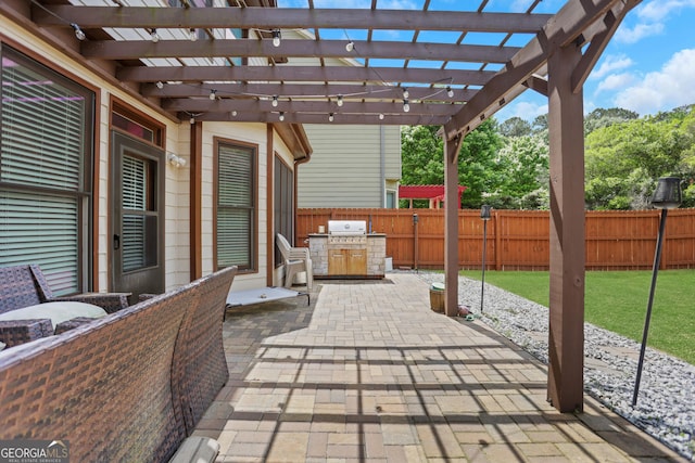 view of patio featuring a fenced backyard, a pergola, and an outdoor kitchen