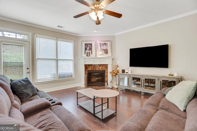 living room with a ceiling fan, ornamental molding, visible vents, a high end fireplace, and wood finished floors