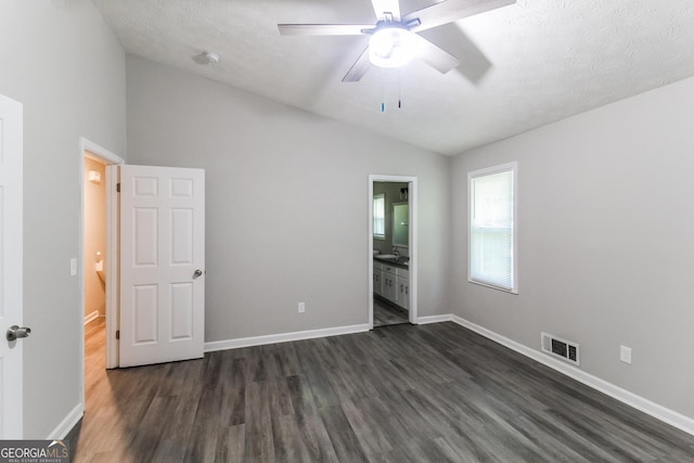 unfurnished bedroom with lofted ceiling, dark wood-style flooring, baseboards, and visible vents