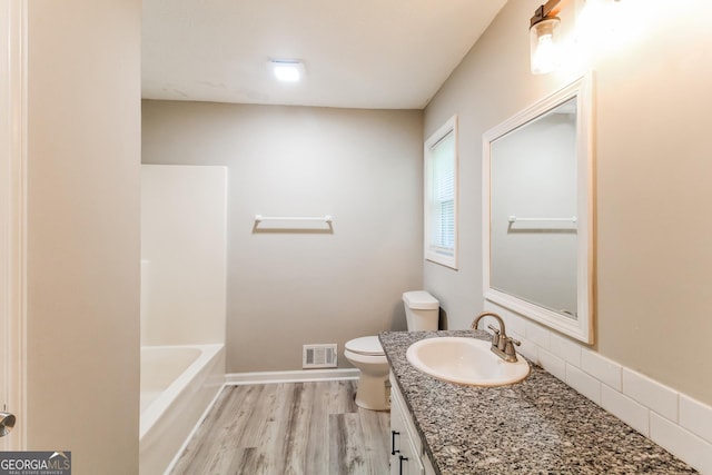 bathroom featuring toilet, wood finished floors, vanity, visible vents, and backsplash