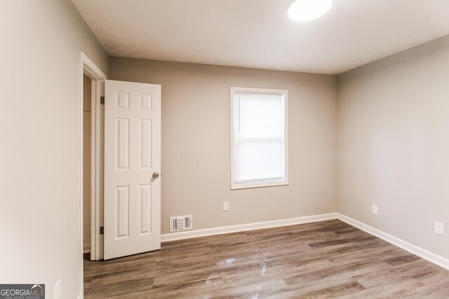unfurnished room featuring visible vents, wood finished floors, and baseboards