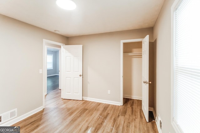 unfurnished bedroom featuring baseboards, a closet, light wood-style flooring, and visible vents