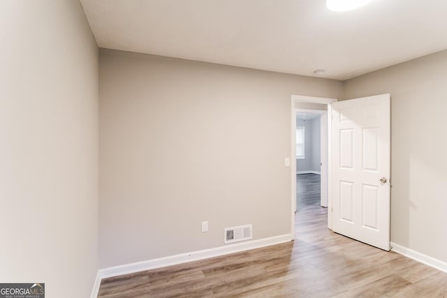 empty room featuring light wood-style floors, visible vents, and baseboards