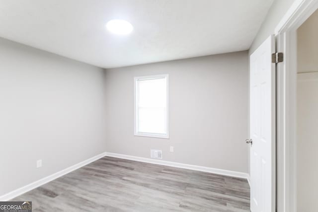 spare room featuring baseboards, visible vents, and wood finished floors