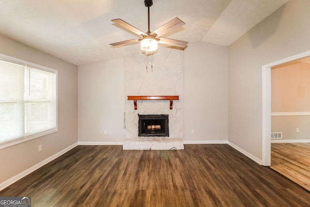 unfurnished living room with wood finished floors, baseboards, ceiling fan, a stone fireplace, and vaulted ceiling
