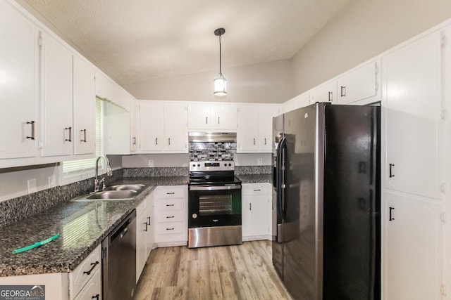 kitchen with under cabinet range hood, a sink, vaulted ceiling, light wood-style floors, and appliances with stainless steel finishes