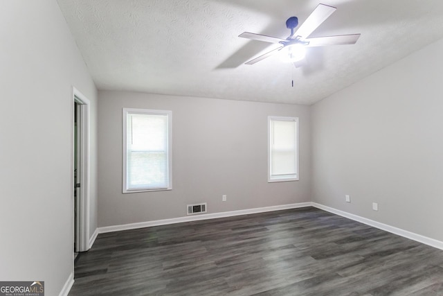 unfurnished room with plenty of natural light, baseboards, dark wood-type flooring, and visible vents