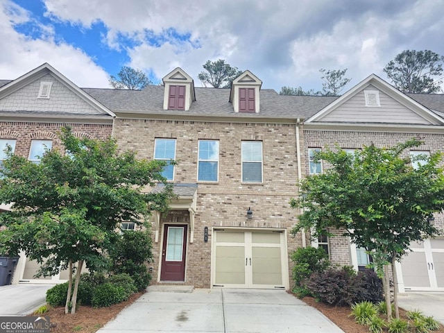 townhome / multi-family property with concrete driveway and brick siding