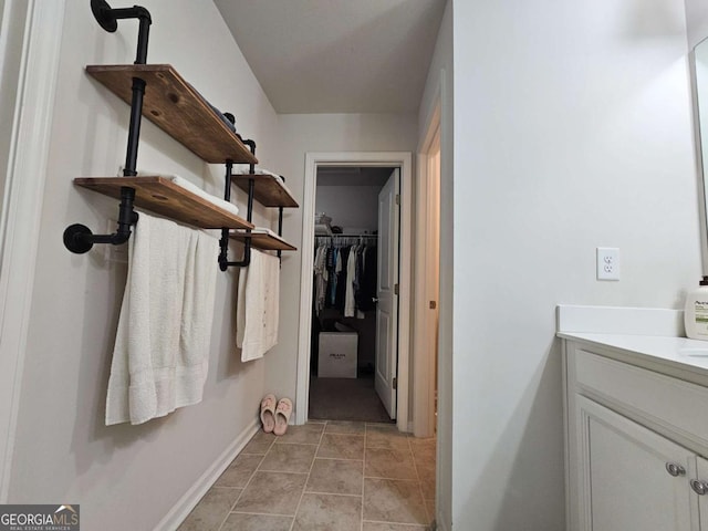 bathroom featuring baseboards, a spacious closet, and vanity