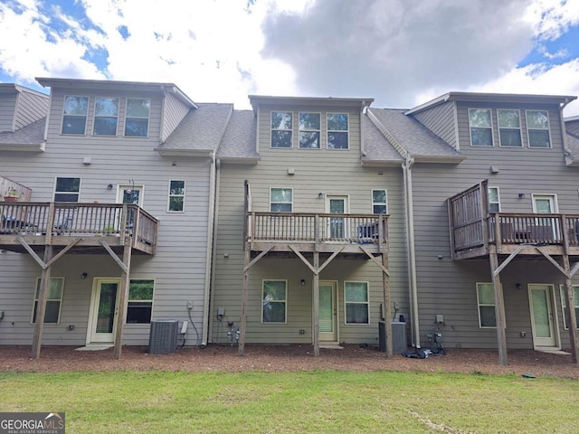 back of property featuring a lawn, central air condition unit, a shingled roof, and a deck