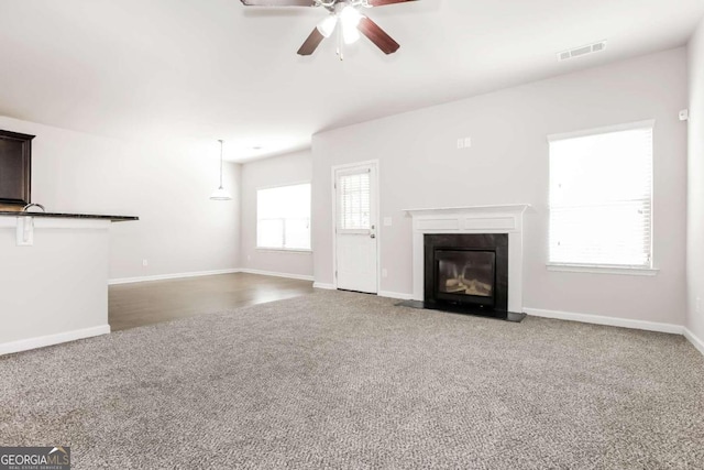 7843 Shertall St, Fairburn, GA 30213 - unfurnished living room featuring carpet flooring, a fireplace with flush hearth, visible vents, baseboards, and ceiling fan