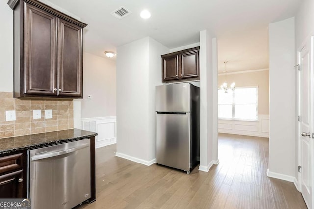 7843 Shertall St, Fairburn, GA 30213 - kitchen featuring dark brown cabinets, visible vents, dark stone countertops, light wood-style floors, and stainless steel appliances