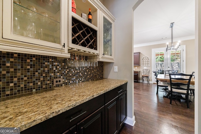 621 Oakbourne Way, Woodstock, GA 30188 - indoor dry bar featuring crown molding, tasteful backsplash, baseboards, dark wood-style flooring, and arched walkways