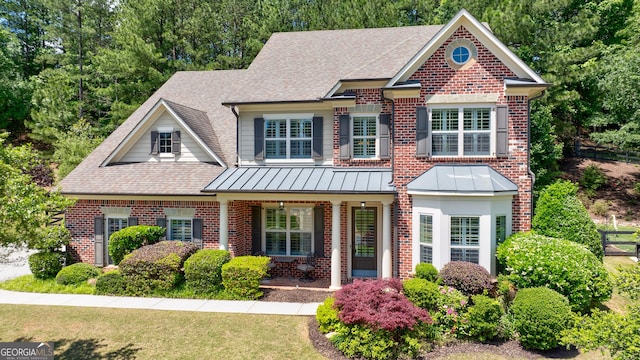 621 Oakbourne Way, Woodstock, GA 30188 - craftsman-style home with brick siding, roof with shingles, a porch, and a standing seam roof