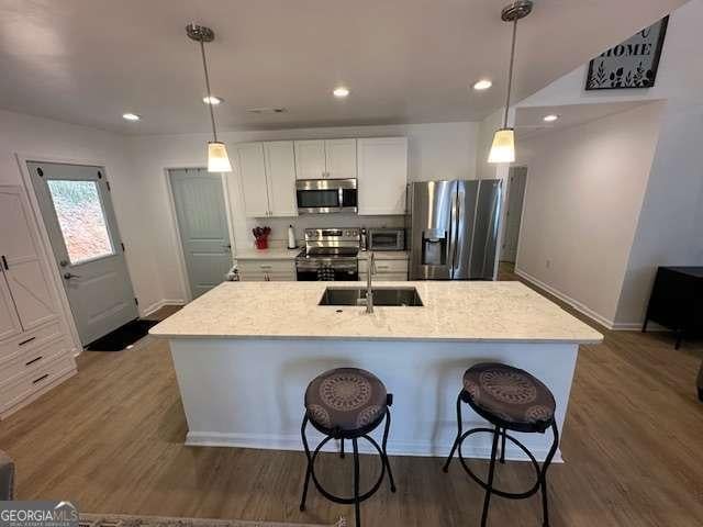 kitchen with a sink, stainless steel appliances, baseboards, and white cabinets