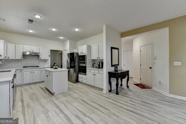 kitchen with oven, visible vents, gas cooktop, under cabinet range hood, and fridge with ice dispenser