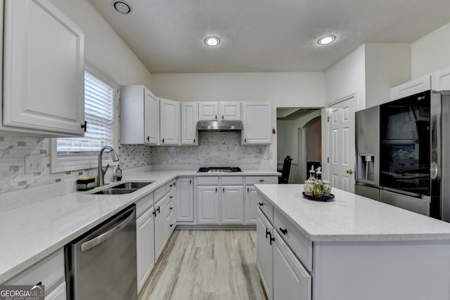 kitchen featuring gas stovetop, a sink, white cabinetry, under cabinet range hood, and dishwasher
