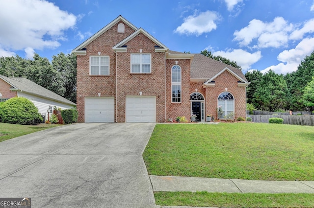traditional-style home featuring a garage, fence, concrete driveway, a front yard, and brick siding