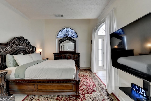 bedroom with light wood finished floors, a textured ceiling, and visible vents