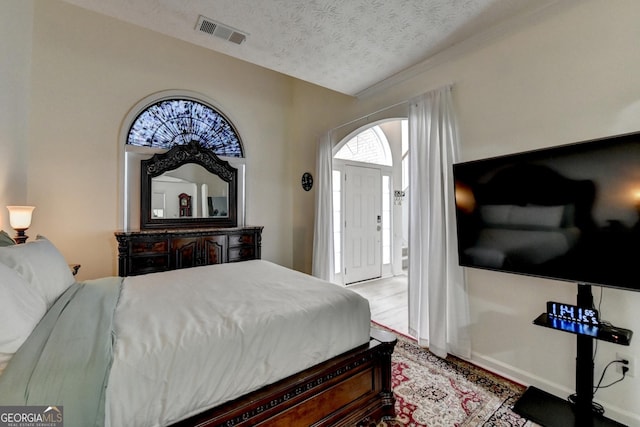 bedroom featuring a textured ceiling, visible vents, and wood finished floors
