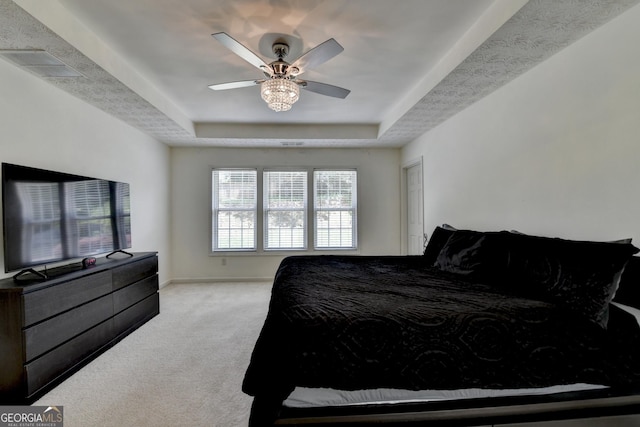 carpeted bedroom with a tray ceiling, ceiling fan, baseboards, and visible vents