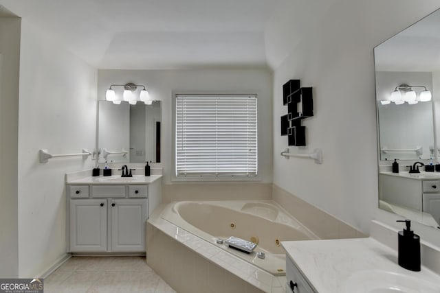 full bath featuring a tub with jets, tile patterned flooring, two vanities, and a sink
