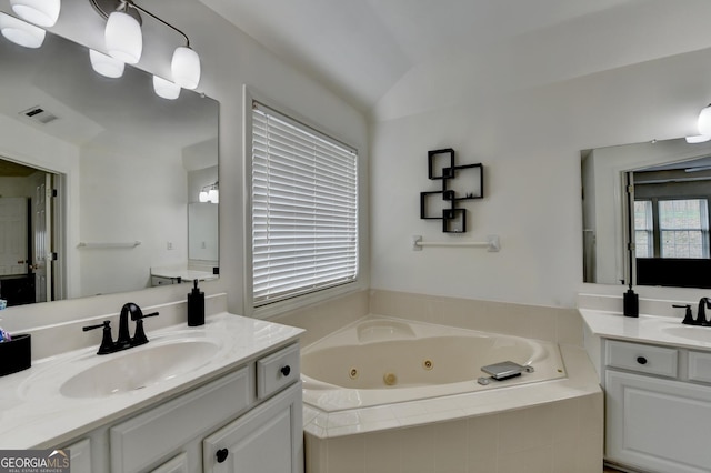 full bathroom featuring two vanities, a jetted tub, visible vents, and a sink