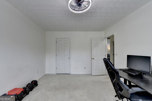 office space featuring light colored carpet, a textured ceiling, and baseboards