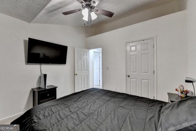 bedroom with lofted ceiling, a textured ceiling, baseboards, and a ceiling fan
