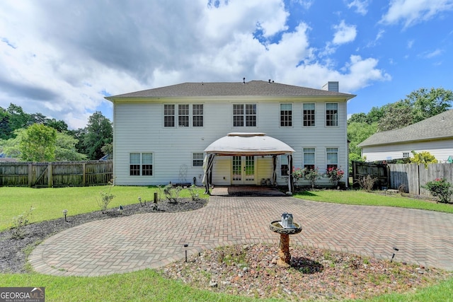 back of property featuring a yard, a chimney, french doors, a patio, and a fenced backyard