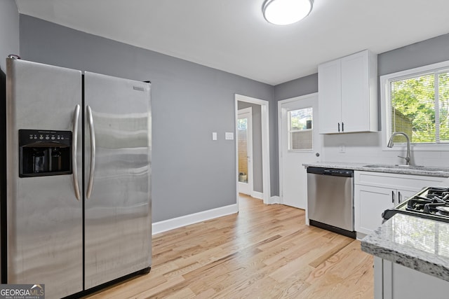 kitchen featuring white cabinetry, appliances with stainless steel finishes, light stone countertops, and a sink