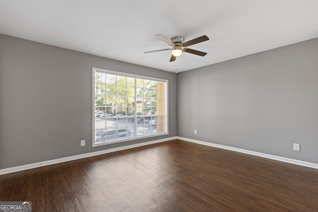 empty room featuring baseboards, a ceiling fan, and dark wood-style floors