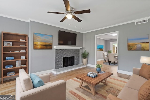 living area featuring ornamental molding, visible vents, ceiling fan, baseboards, and light wood-style floors