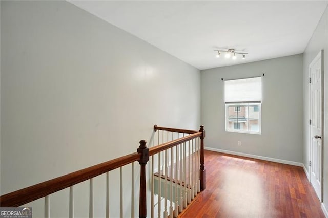 hall featuring baseboards, an upstairs landing, and wood finished floors