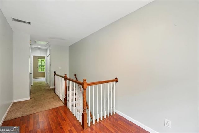 stairway with attic access, wood finished floors, visible vents, and baseboards